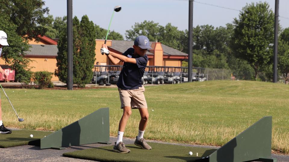 Boy hitting golf ball at driving range