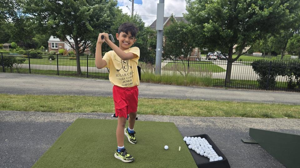 Boy swinging a golf club at a driving range